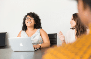 A woman laughing while using a laptop computer