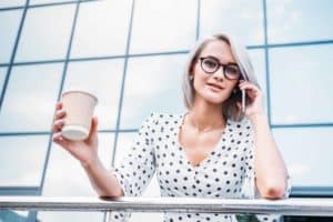 A woman holding a cup of coffee while talking on a cell phone