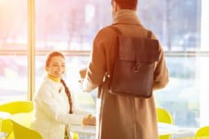 A woman standing in front of a man at a table