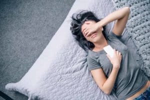A woman laying on top of a bed next to a pillow