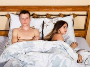 A man and a woman laying in bed under a blanket